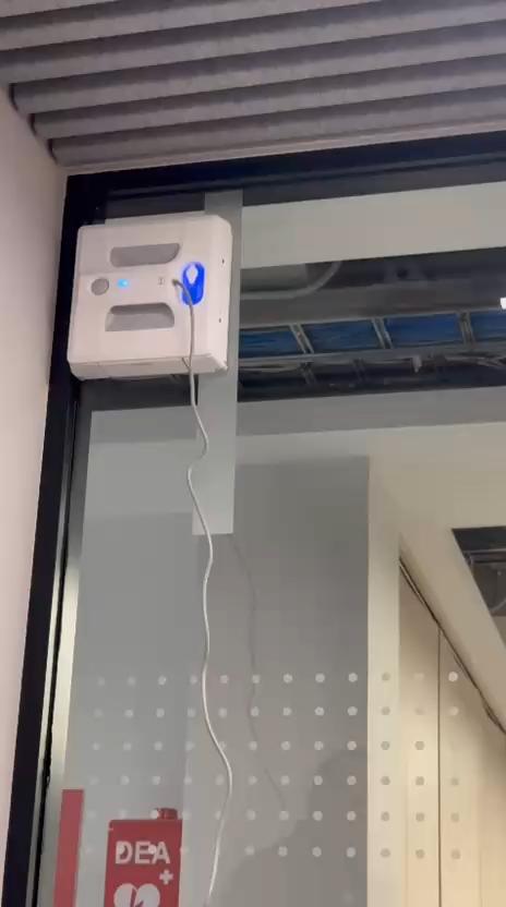 Robot ventanal adherido a una mampara de vidrio